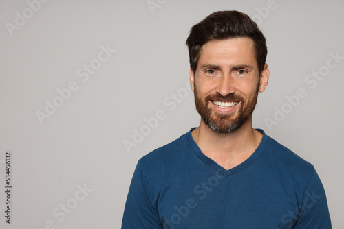 Portrait of happy bearded man on grey background. Space for text