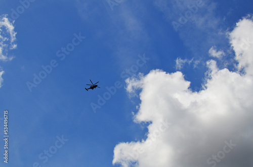 Modern helicopter flying in blue cloudy sky  low angle view