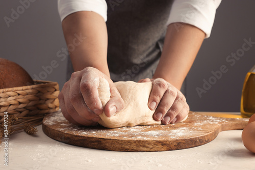 Man kneading dough at table near grey wall, closeup