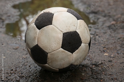 Dirty soccer ball near puddle on ground  closeup