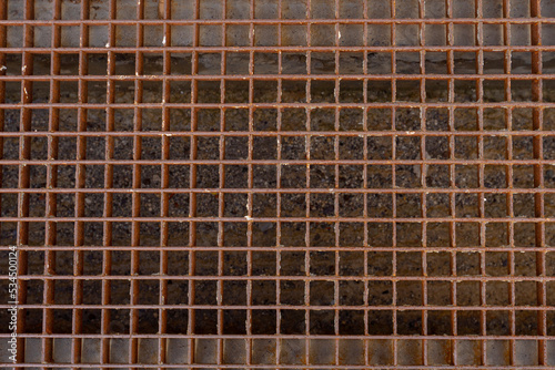 Close-up of the metal grating of the sewer drain, rusted with time. The infrastructure of a big city. sewer grate.