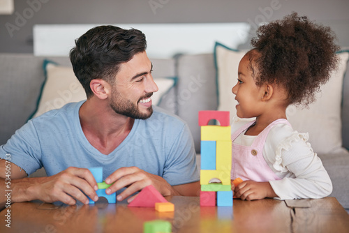 Children, family and education with a girl and her father playing with building blocks in the living room of their home. Love, learning and toys with a foster parent and adopted child together