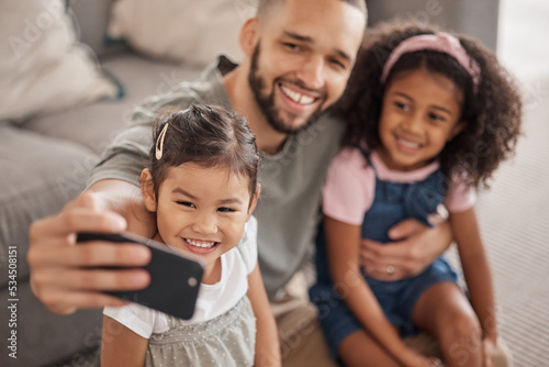 Love, father and children selfie on smartphone for cute bonding memory together in living room. Social media photograph of Mexican dad and young children relaxing in family home on weekend.