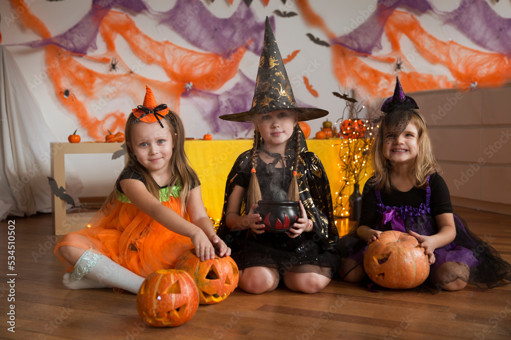 Fototapeta premium happy three Child girls in witch costume Halloween trick or treat. Home festive autumn season holiday decoration. Halloween party