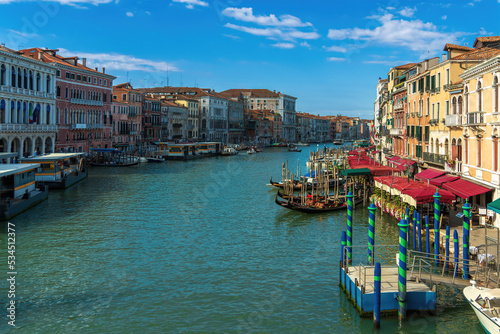 Motor boats and gondolas on a wide canal street in Venice, vintage houses and summer restaurants on a Venetian street on a sunny morning, houses on the banks of a canal in the city of Venice