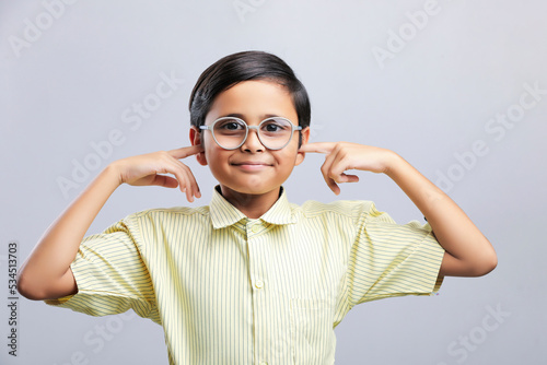 Indian school boy finger in ear and giving cant hearing gesture.