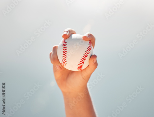 Baseball, athlete hands and ball sports while showing grip of pitcher against a clear blue sky. Exercise, game and softball with a professional player ready to throw or pitch during a match outside photo