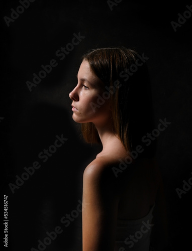 Low key portrait of a young girl in profile