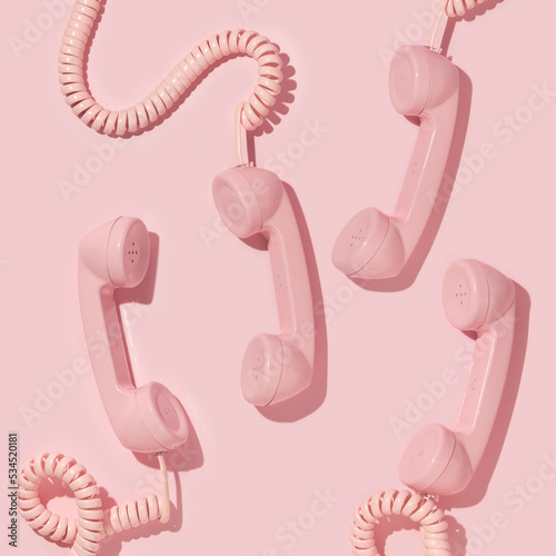 Creative layout with pink retro phone handsets on pastel pink background. 80s or 90s retro fashion aesthetic telephone concept. Minimal romantic handset idea. Valentines day idea.