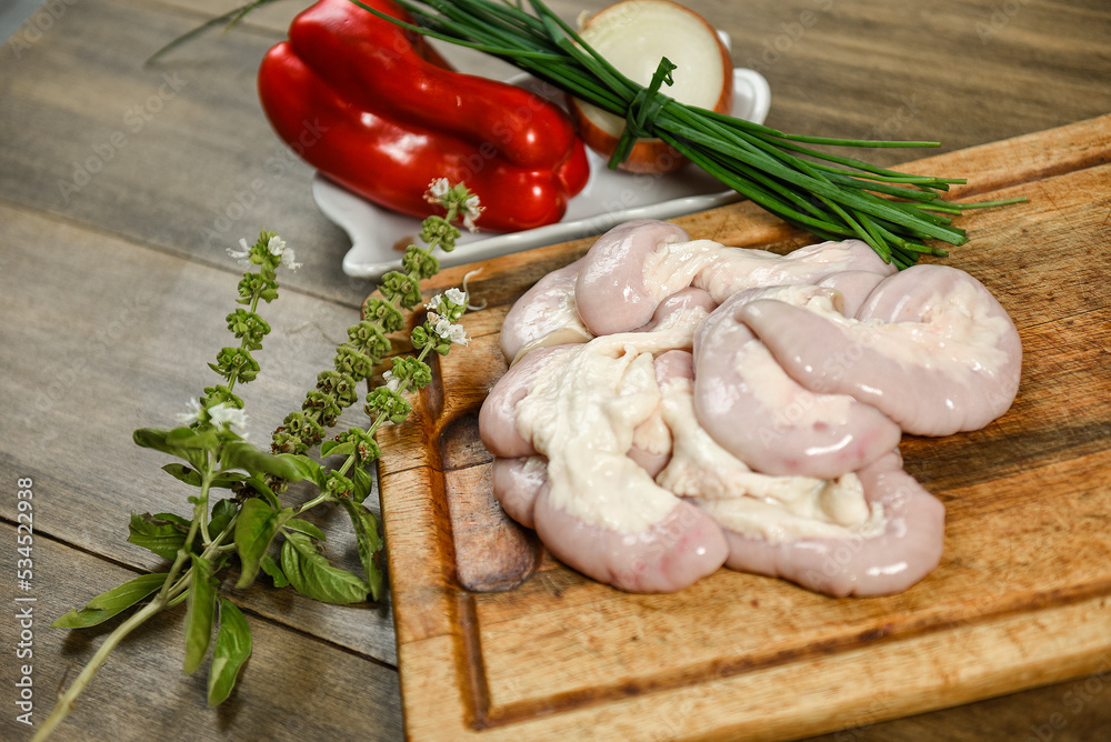 Cow bowels presented on a wooden board with ingredients, ready to grill Cow bowels presented on a wooden board with ingredients, ready to grill