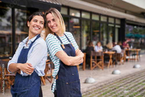 Portrait of two happy female restaurant business owners posing and having fun in front of their restaurant