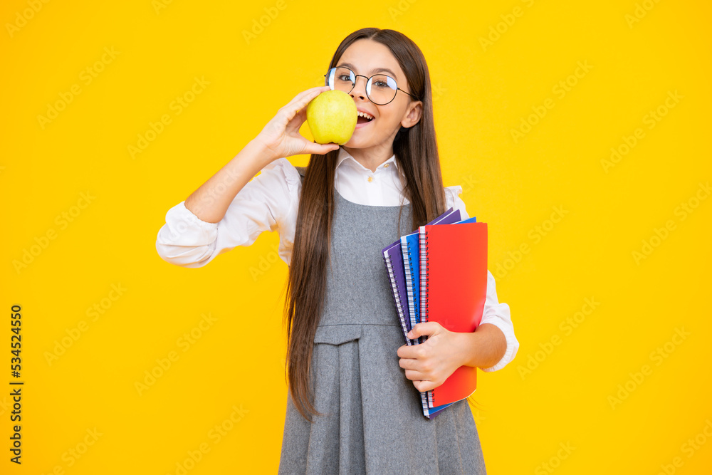 Back to school. Teenage school girl with bag hold apple and book, ready to learn. School child on isolated yellow studio background. Back to school. Teenage school girl with bag hold apple and book, ready to learn. School child on isolated yellow studio background.