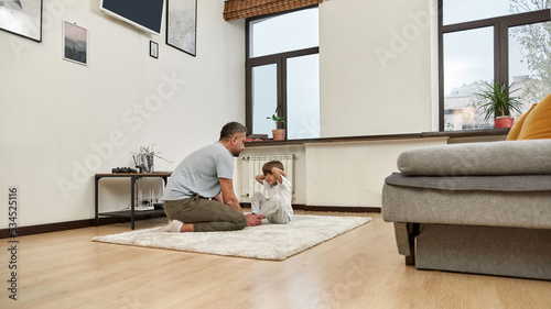 Dad teaching son doing press ups on carpet at home photo