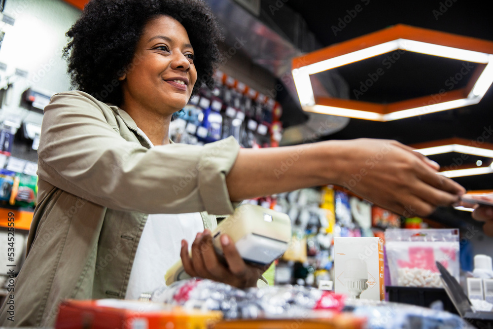 Fototapeta premium African American hardware shop worker charging on credit card to customer