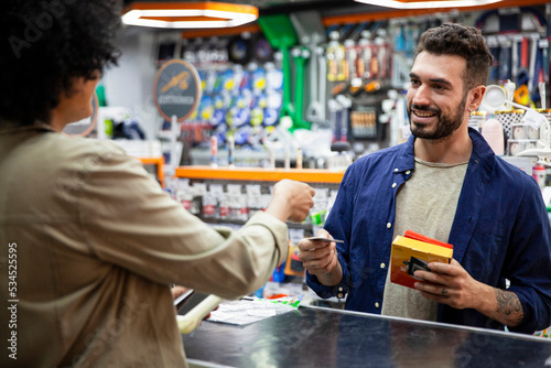 Male customer paying with credit card to African American hardware shop worker