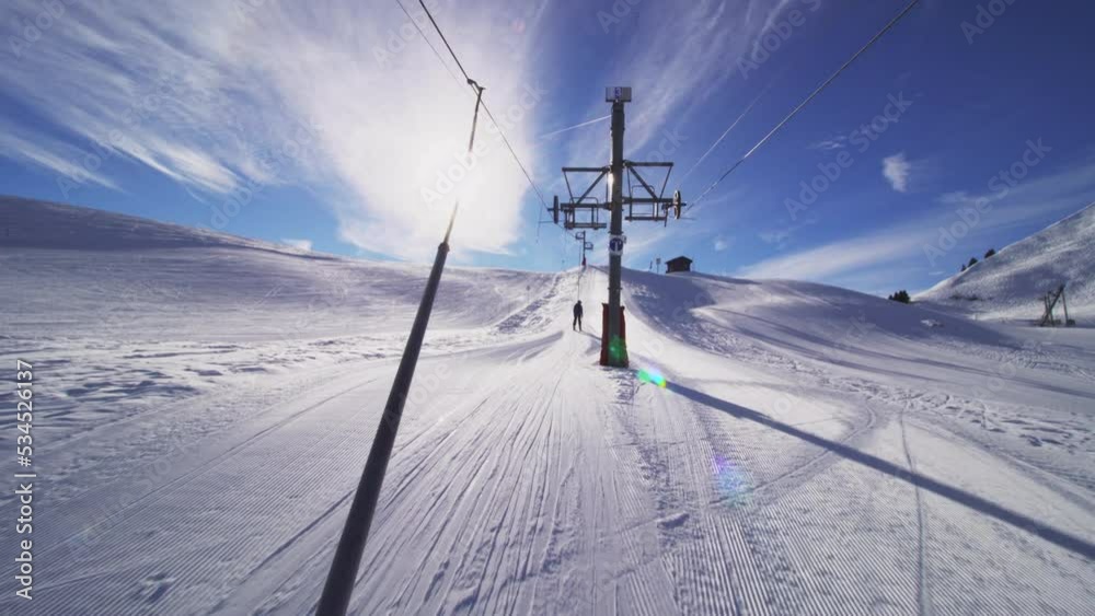 Riding on a ski lift next to a piste in the Swiss Alps. Riding on a ski lift next to a piste in the Swiss Alps.