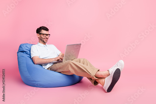 Full length photo of positive man sitting chair online meeting conference dating enjoy device empty space isolated on pink color background