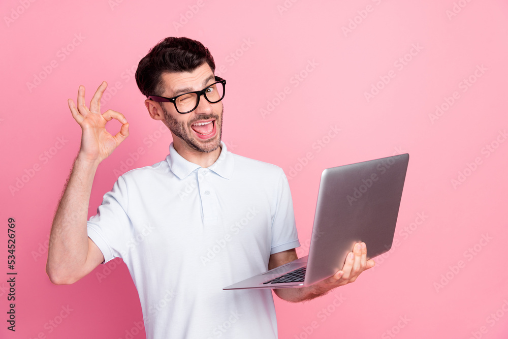 Photo of satisfied attractive man use modern device gadget recommend netbook wink eye empty space isolated on pink color background Photo of satisfied attractive man use modern device gadget recommend netbook wink eye empty space isolated on pink color background