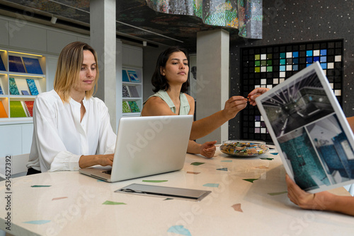 Two young female home decor entrepreneurs sitting at their desk with a client