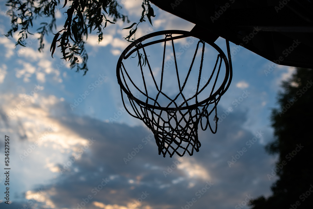 Basketball ring or hoop in a yard. Low angle shot, blue summer sky in the background, no people