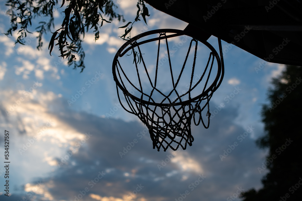 Basketball ring or hoop in a yard. Low angle shot, blue summer sky in the background, no people Basketball ring or hoop in a yard. Low angle shot, blue summer sky in the background, no people