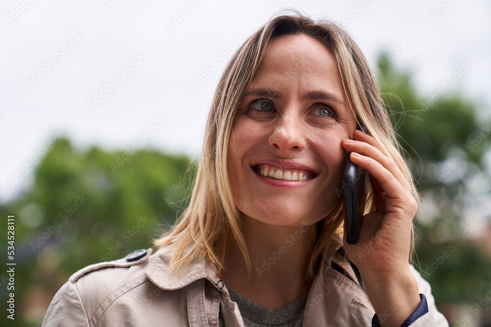 Close-up shot of smiling woman speaking on cell phone in the street Close-up shot of smiling woman speaking on cell phone in the street
