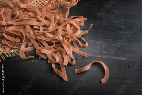 Whole grain tagliatelle, healthy pasta with more fiber, protein, B vitamins and minerals, dark wooden table, copy space, top view from above photo