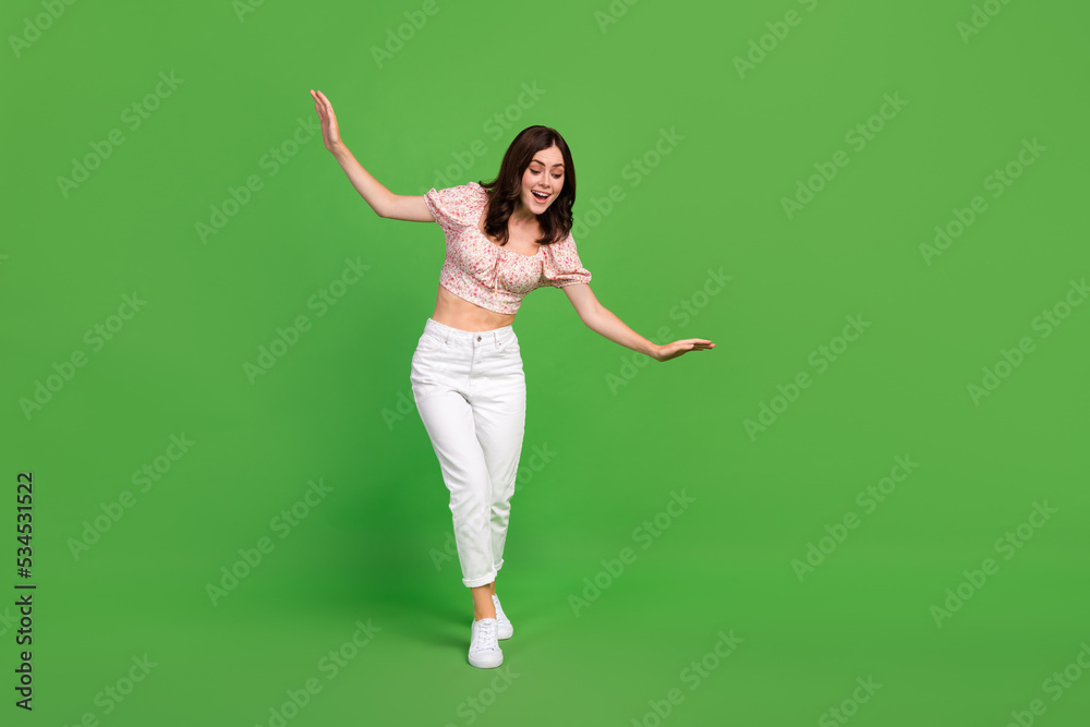 Full size photo of nice cheerful woman with curly hairdo wear white trousers top look down isolated on green color background Full size photo of nice cheerful woman with curly hairdo wear white trousers top look down isolated on green color background