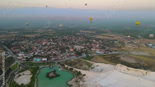 Landscape of Pamukkale park and a lot of hot air balloons in the morning sky.
