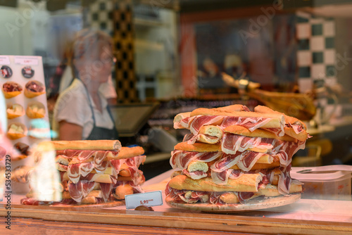 Store window with trays of serrano ham bread sandwiches.