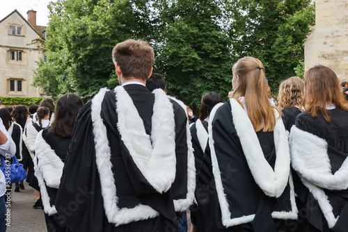 back view of Male and female fresh graduate students with gown and academic address walk in campus of Cambridge University, UK during congregation day.