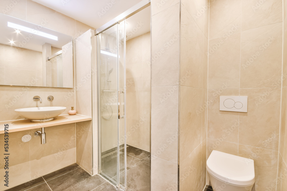 Light bathroom with tiled walls and shower cabin near cabinet Light bathroom with tiled walls and shower cabin near cabinet