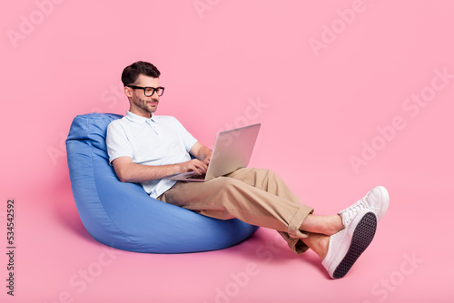 Full length photo of concentrated serious man sit chair enjoy fast 4g texting modern device empty space isolated on pink color background