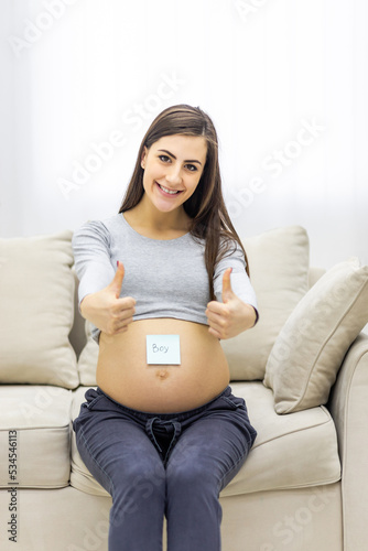 Photo of pregnant woman holding a paper with sex of the child.