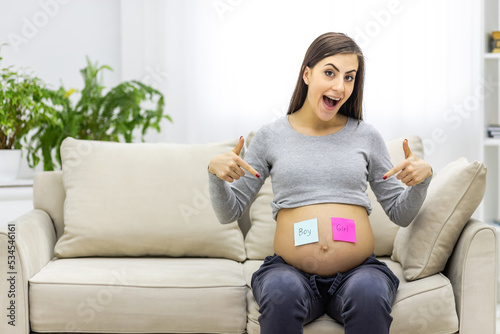 Photo of positive pregnant woman with pink and blue papers on the stomach