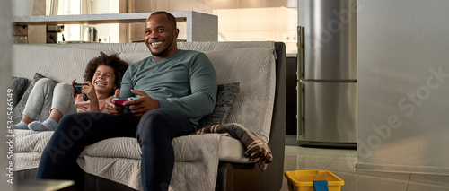 Black cheerful boy and father playing video game