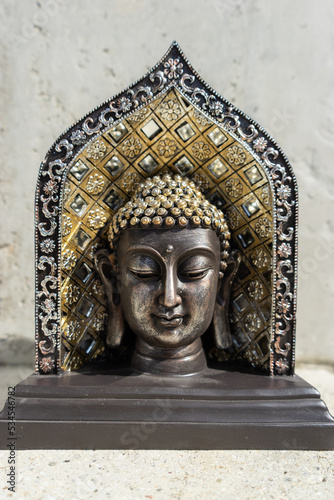Buddha statue near house in front of wall.