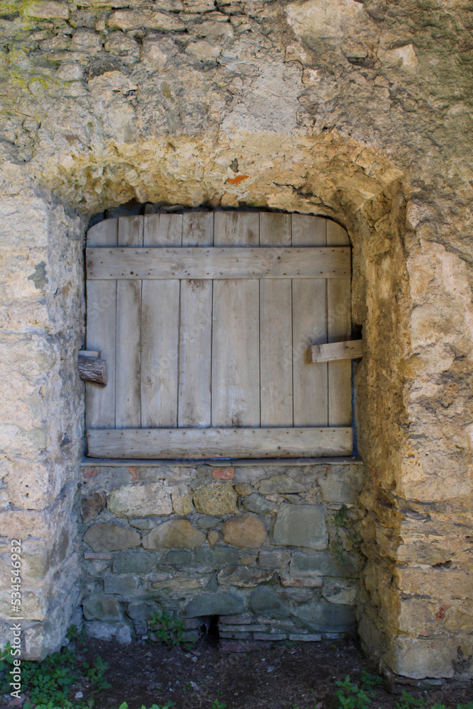 Vecchia finestrella tra le pietre con imposta di legno