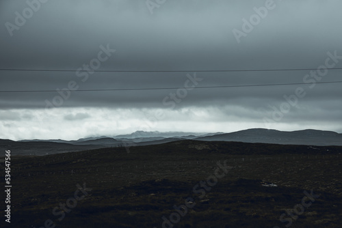 ROad trip in the center of the Island of Lewis and Harris in a moody, overcast gloomy and rainy day. Misty hills in the distance, electric lines and middle of nowhere felling.