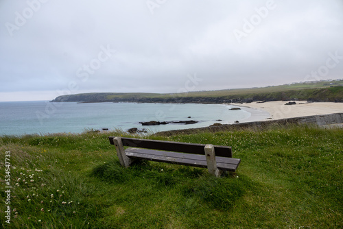 Wide angle view of Port Ness beach and a wooden bench in a looking point. Gloomy hebridean summer views.