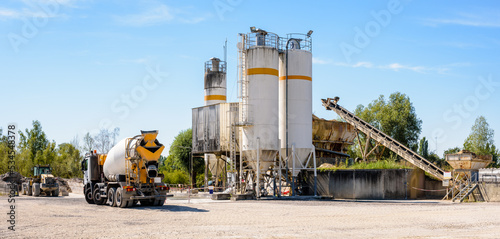 Foto A concrete mixer truck and a wheel loader are parked next to sand silos in a quarry on a sunny day
