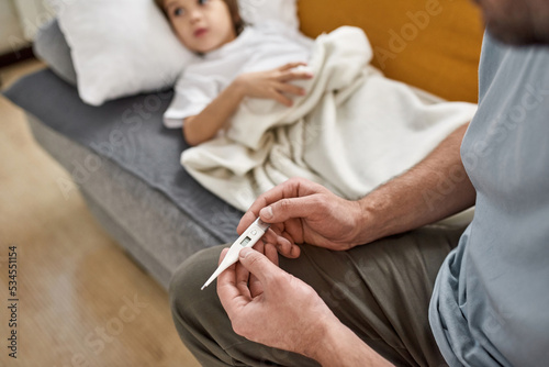 Thermometer in hands of father near sick son