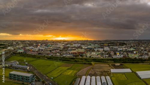Aerial view of rice fields next to town under storm clouds at sunset