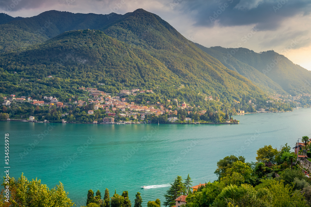 Idyllic Lake Como coastline with village and boat at sunset, Northern Italy
