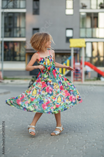 Child girl runs, spins, spins and dances on street in summer. Childhood and vacation concept. © Olha Tsiplyar