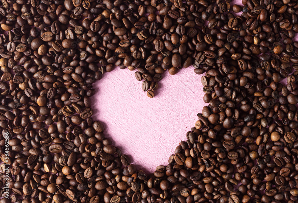 Coffee background made of beans with a pink heart laid out Coffee background made of beans with a pink heart laid out