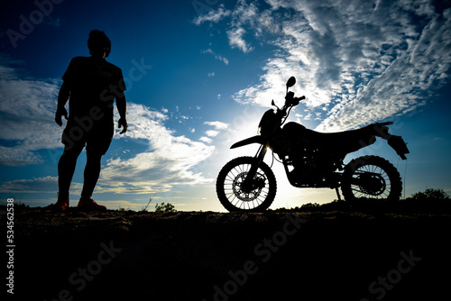 Silhouette Man enjoying a motocross bike on a beautiful evening in the mountains.