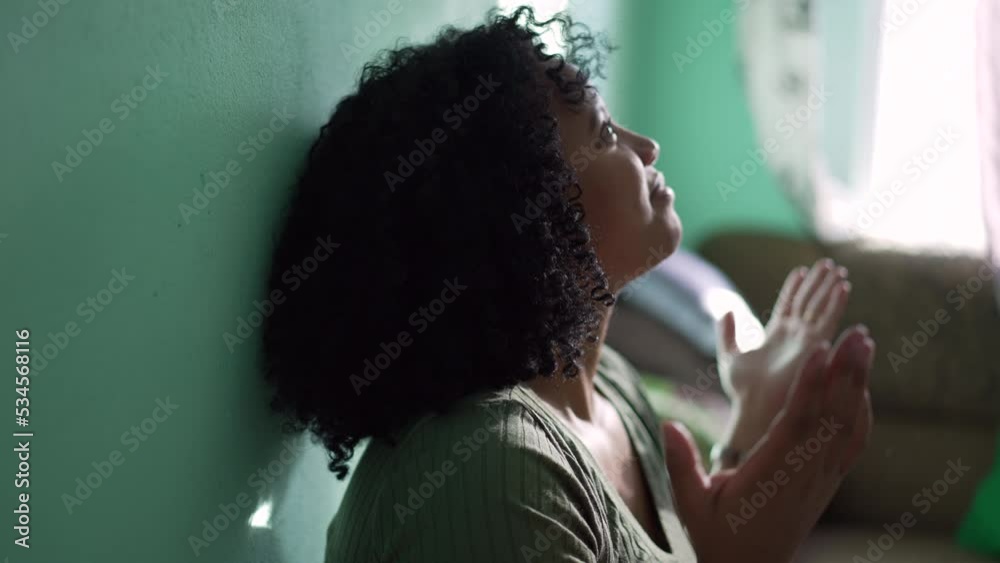 One Evangelical young black woman in praying to GOD raising hands in the air surrendering to a higher power