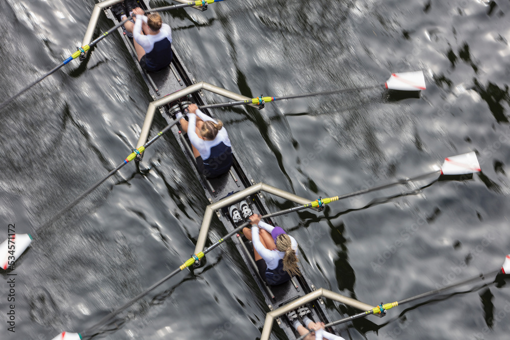 © Mint Images - Overhead view of female crew racers rowing in an octuple racing shell, an eights team.