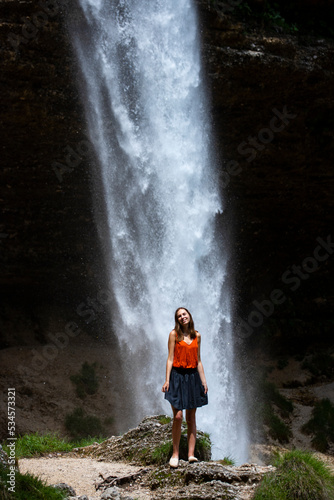 beautiful woman in blue skirt standing in front of large waterfall in slovenia, closeup photography of pretty woman with huge waterfall in the background (Peričnik)